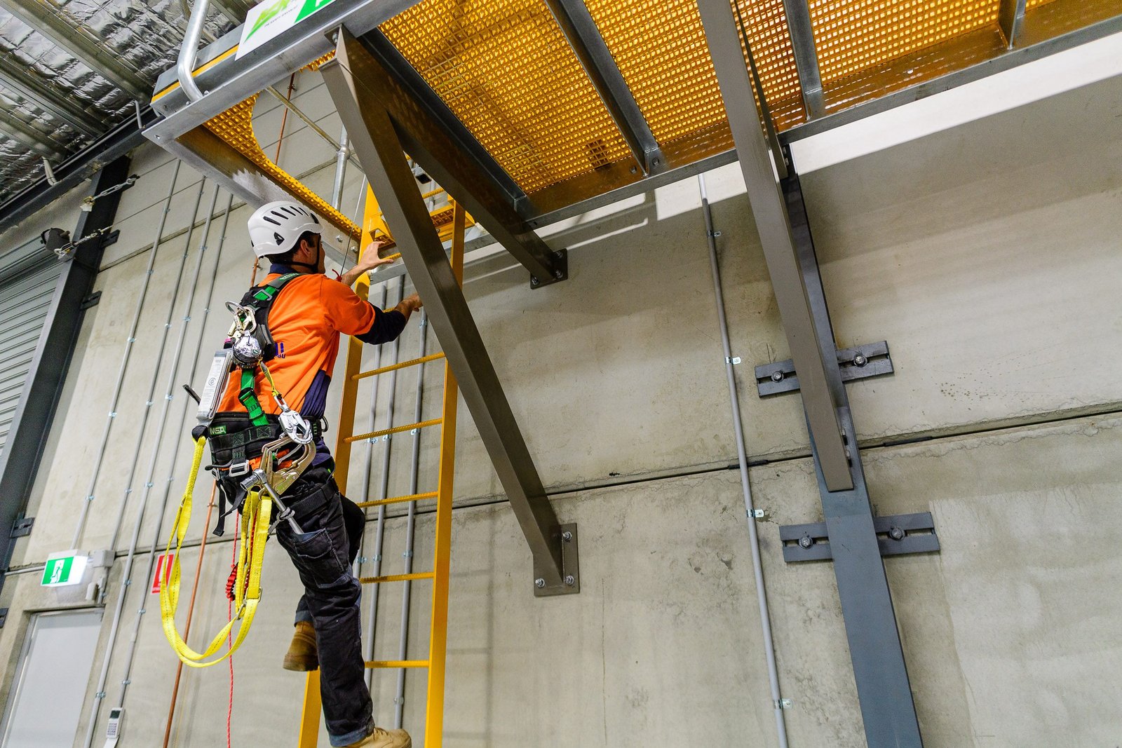 Worker in a harness climbing a ladder during face-to-face heights training